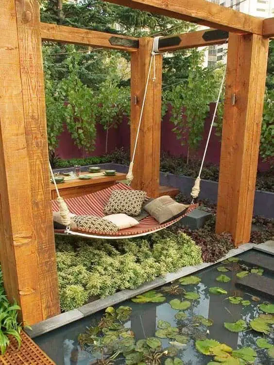 Outdoor Daybeds like this Asian-inspired design with a swinging hammock, koi pond and beautiful plants that surround a minimalist, sturdy frame make for a peaceful setting.